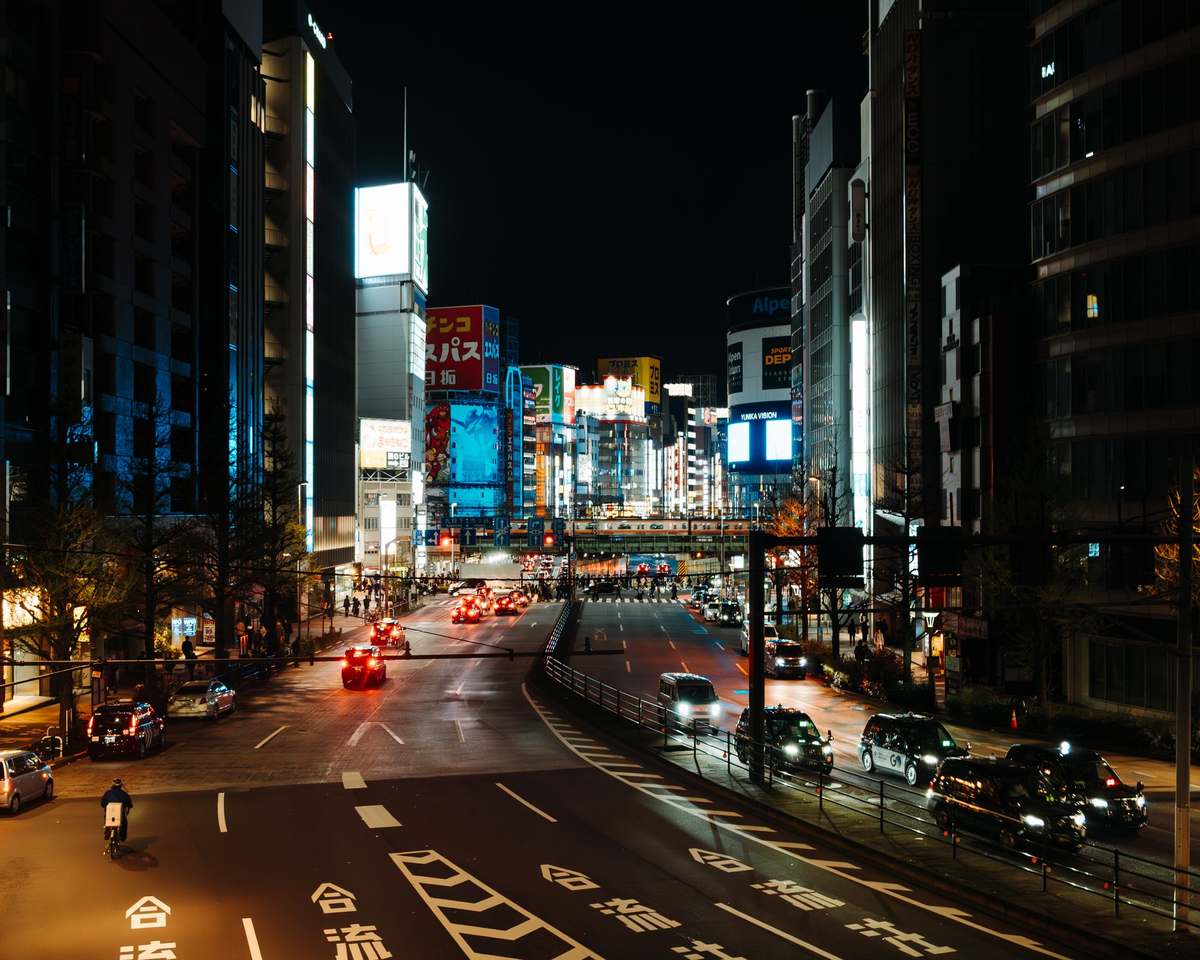 Neon-lit Tokyo street at night with traffic and illuminated signs