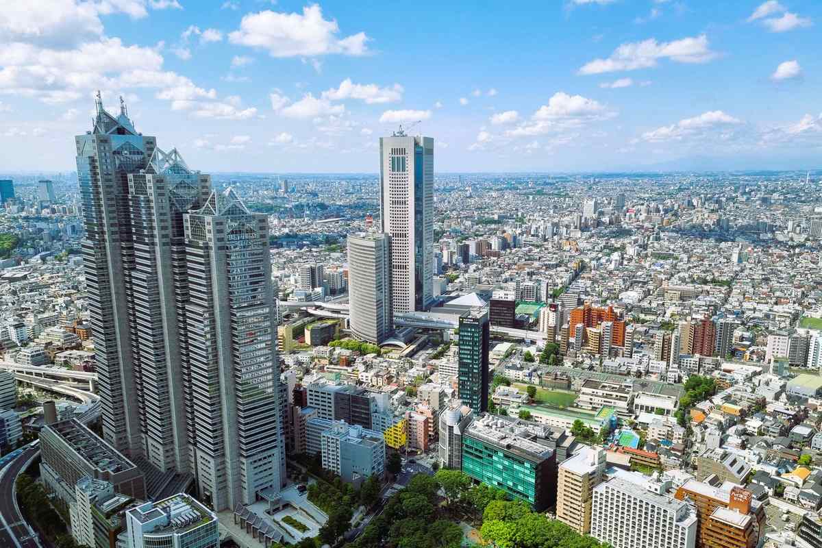 Aerial view of Shinjuku high-rises and dense Tokyo neighbourhoods under a blue sky