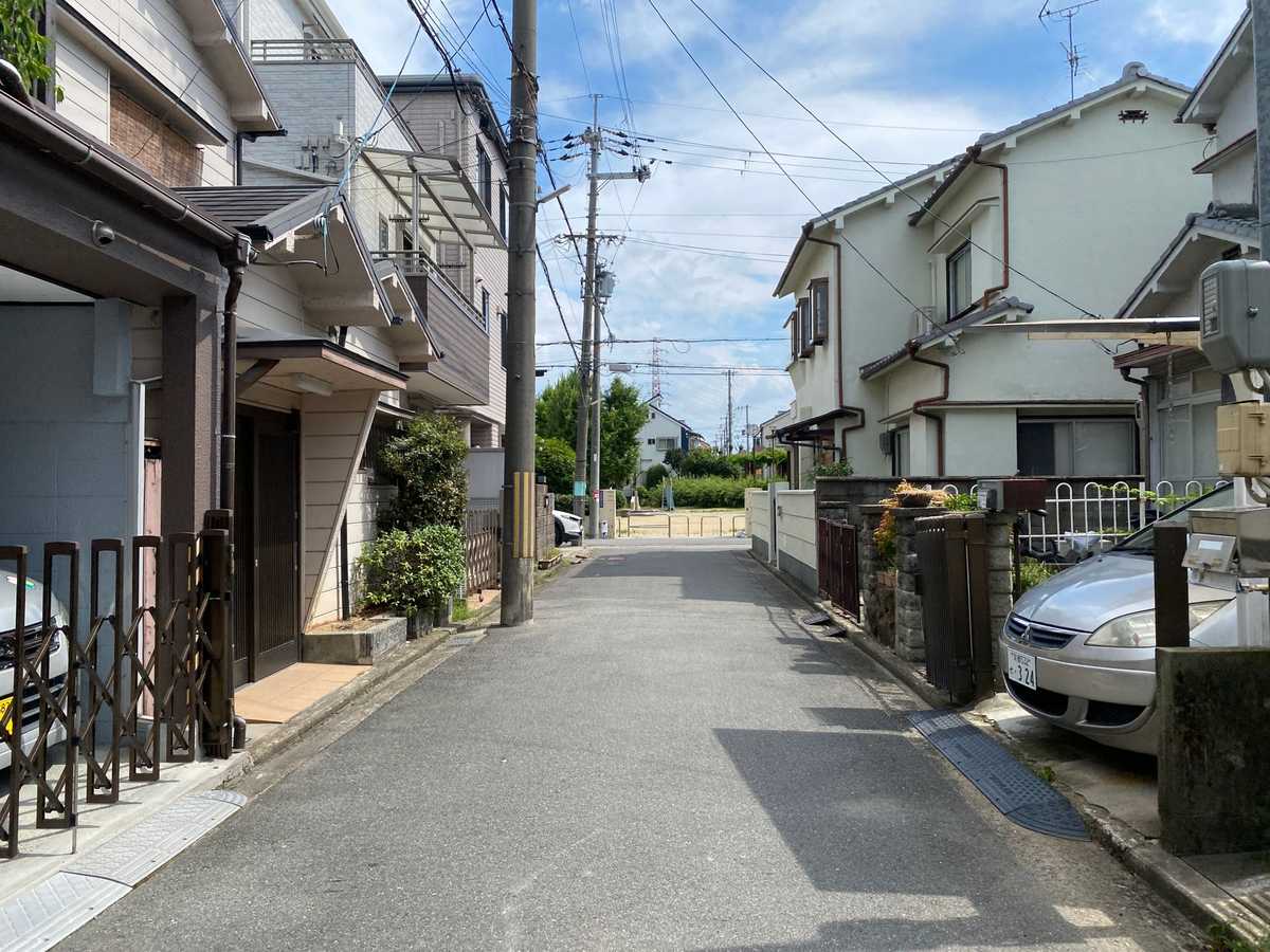 Quiet residential street lined with detached houses under a blue sky in suburban Japan