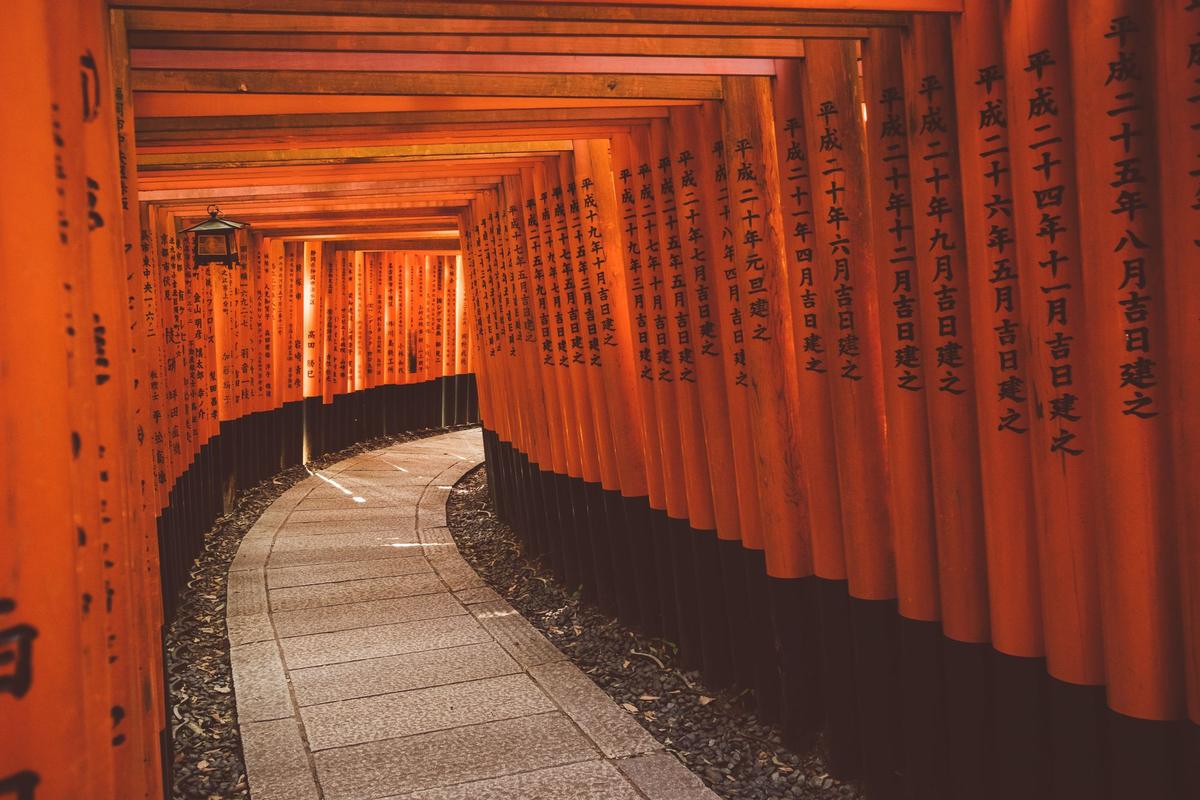 Tunnel of vermilion torii gates with inscribed pillars at Fushimi Inari Shrine, Kyoto